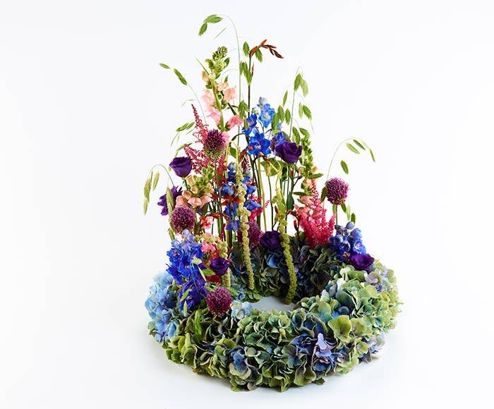 Begravelseskrans med hortensia og farverige detaljer.