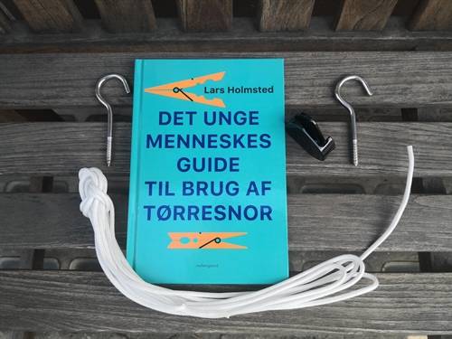 Det unge menneskes guide til brug af tørresnor. Bog af Lars Holmsted. + 10 meter tørresnor, 2 tøjsnorkroge og en tørresnorstrammer.