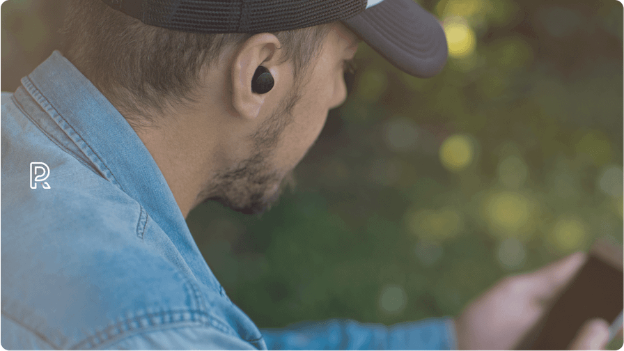 An image of a man with earbuds, looking at the phone