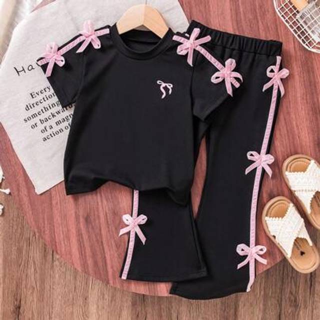 SHEIN Girls Sweet And Cool Ballet Style Black Short Sleeve T-Shirt + Flare Pants Set. The Top Features A Playful Pink Bow Accent On The Shoulder, Simple Yet